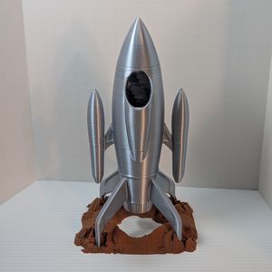 The back of the dice tower, showing the hole where the dice go in towards the top, just under the conical tip of the rocket.