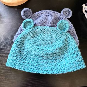 Two baby beanies with bear ears in the colors Teal (12) and Blue (08) from the Acacia yarn swatch options. 