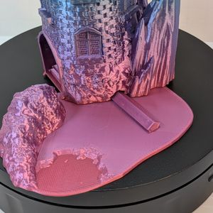 A close-up of the removable base to the dice tower. It shows the pentagon-shaped key on the dice catcher tray that slides into the base of the tower itself.