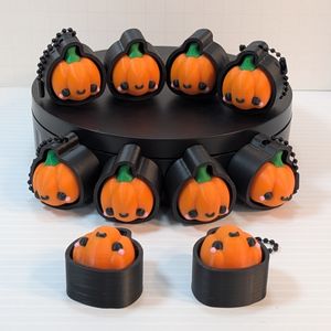 A display of ten pumpkin clickers, half with chains, half without. They are showing different angles of the clicker.