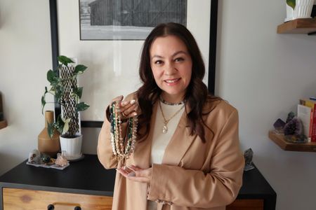 The designer and maker of Auréad Designs holding a selection of gemstone necklaces.