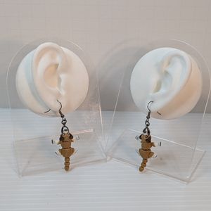 The dog earrings hanging off the earlobes of white silicone display ears, showing how they dangle.