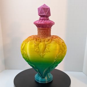 A 3D printed "bottle" in the shape of a heart, with a D2 on the capper on the top. It's in a rainbow gradient filament, and it has fancy scrollwork down the sides and around the neck.