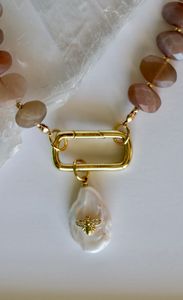 Closer look at the gold carabiner clasp and removable pearl & bee charm on the Lucent Necklace