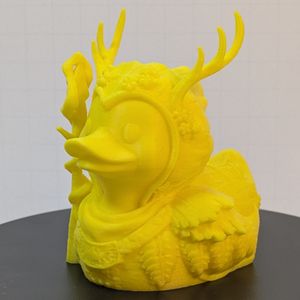 A 3D printed duck, in the style of a rubber ducky. It's dressed as a fantasy druid, with antlers coming out of their hood, armor shaped like leaves, and they're carrying a twisted wooden staff.