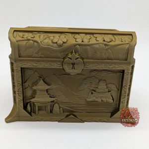 A golden colored 3D printed dice box, in the shape of a chest. There is a fake lock on the front, with images of Chinese architecture and trees on water.