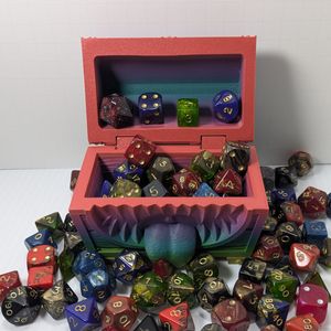 The 3D printed dice vault, open, filled with and surrounded by colorful TTRPG dice.