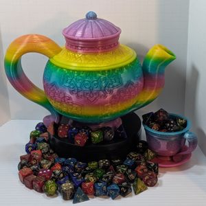 A 3D printed teapot, tea cup, and saucer. The teapot is on a black circular stand, surrounded by colorful TTRPG dice. The cup and saucer are sitting underneath the spout, and the cup is filled with dice, as well.