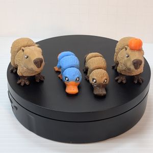 Four 3D printed critters, with articulation on their legs, necks, and middle of their bodies. From left to right, there's a brown capybara, a blue platypus, a brown platypus, and a brown capybara with a yuzu fruit on its head.
