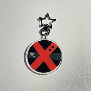 Keychain with design of Bakugou’s hero suit with gunmetal gray star clasp on white tabletop