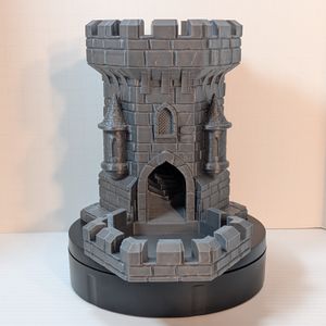 The front of the dice tower. There are two smaller turret towers on the sides, and a wide open arch door for the dice to exit out of into the tray at the bottom.