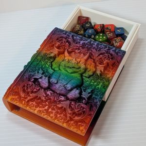 The tome laying flat, with the pages partially slide out the top to show dice stored inside. At the bottom of the tome, you can see one of the magnets used to hold the pages in place.