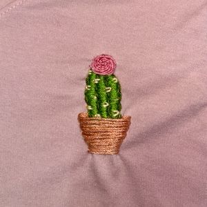 Close up of cactus embroidery design in green cactus in brown pot with a pink flower on top.