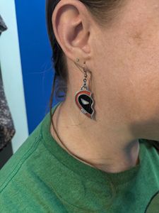 A woman wearing a 3D printed earring that looks like half of a heart. It is styled like half of Deadpool's mask, and it has the word "Best" in small letters at the bottom.