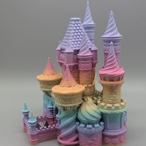 A colorful dice tower in the shape of a castle that makes you think of candy. It has spires and towers all around, and there is a d20 in the catch tray for a sense of scale.