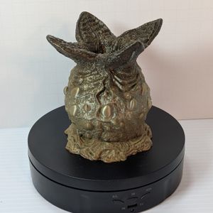 A 3D printed dice container that looks like an alien egg. It's lumpy, and there are four wedges open at the top, where you can drop in your dice. This one is in a green gradient.