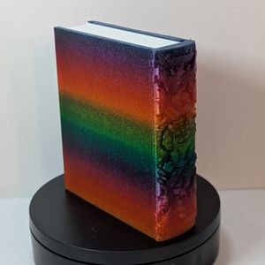 The back and spine of the 3D printed tome. The spine shows a smaller Chomper, surrounded by raised decorative scrollwork. The back is just lightly textured, and shows the gradient of the filament very nicely.