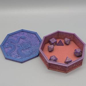 The tray open, with the lid beside the box. It is a polygon shape, and the box itself starts with orange at the bottom, going up to blue and purple on the lid. There is a set of dice inside the box, with room for one or two more sets.
