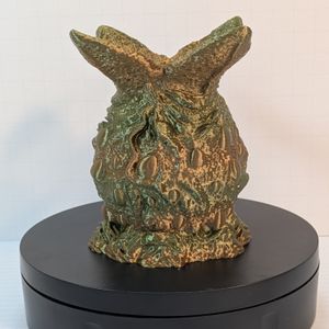 An alien-esque egg, with the top burst open to hold dice, or anything else that would fit. It's in a shining silk filament, in shades of greens and browns.