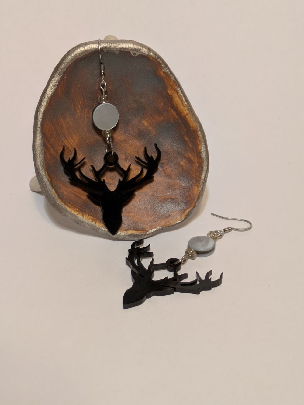 Acrylic stag profile dangling earrings with abalone bead accents
