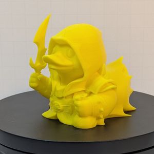 A yellow 3D printed duck in the style of a rubber ducky. It's styled as a fantasy rogue, with a cloak, a coin pouch in one hand, and a dagger in the other.