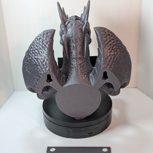 The back of the TP holder. It shows holes for mounting on the wall, and at the bottom of the photo is a 3D printed strip with two holes that can be used to measure out the mounting points.