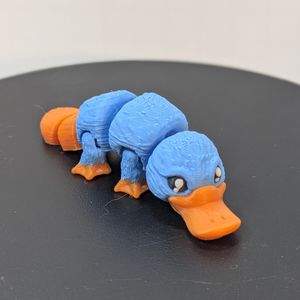 A smaller, 3D printed platypus in blue and orange.