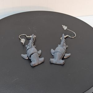 A pair of 3D printed earrings shaped like hammerhead sharks. They have earring hooks attached to their tails, and they're laying with their fins sticking up.