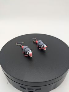 The earrings, standing up on a black rotating stand.
