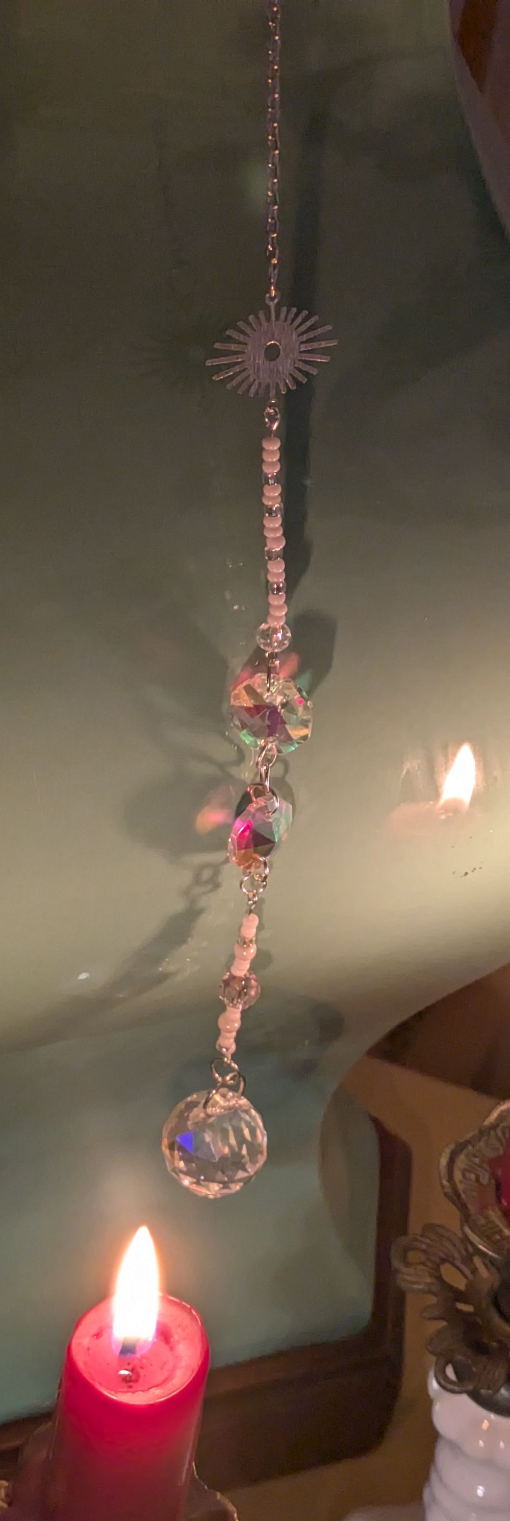 Sun catcher with stylized sunburst symbol and heavy iridescent glass drop