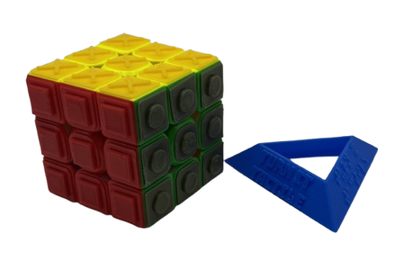 Turn it Tactile 3x3 Speed Cube next to Turn it Tactile Cube Stand. The cube stand is triangular and has Turn it Tactile in print on one side and Turn it Tactile in braille on another