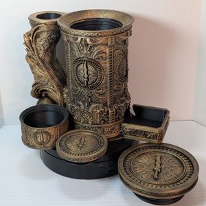 A "tankard" that acts as a dice tower, dice vault, and can holder. It's in a brass rub n buff, and it's disassembled to show the dice tower in the handle, the can in the main cavity, the small dice vault at the side, and the screw-on lid.