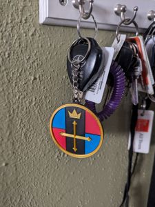 A keyring that's styled after a lion key from the old Voltron series, hanging on a key rack with other keys and keychains.