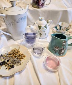 The entire spread of the teacups, teapots, ingredients on a plate, a creamer pitcher, and spare teacups, ready for a mad tea party