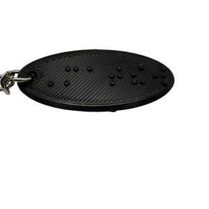 Black oval keychain with the name "Matthew" in braille
