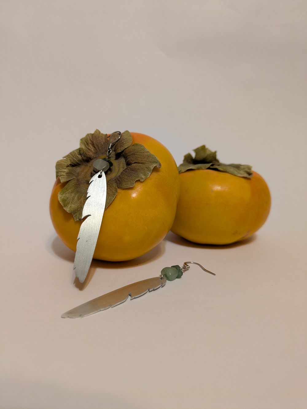 Metal dangling feather earring with natural stone accents