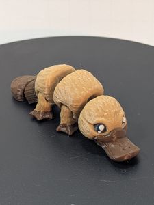 A small, 3D printed platypus in light and dark brown colors.