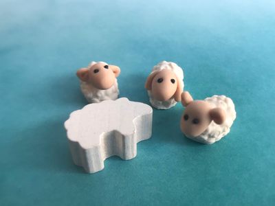 A generic wooden sheep token shown next to a few of my curly sheep. Although roughly the same size, they are a solid improvement!
