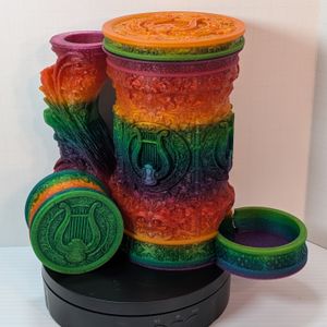 A "tankard" that acts as a dice tower, dice vault, and can holder. It's in a bright rainbow gradient, and it's assembled with the small dice vault that fits inside sitting beside it.
